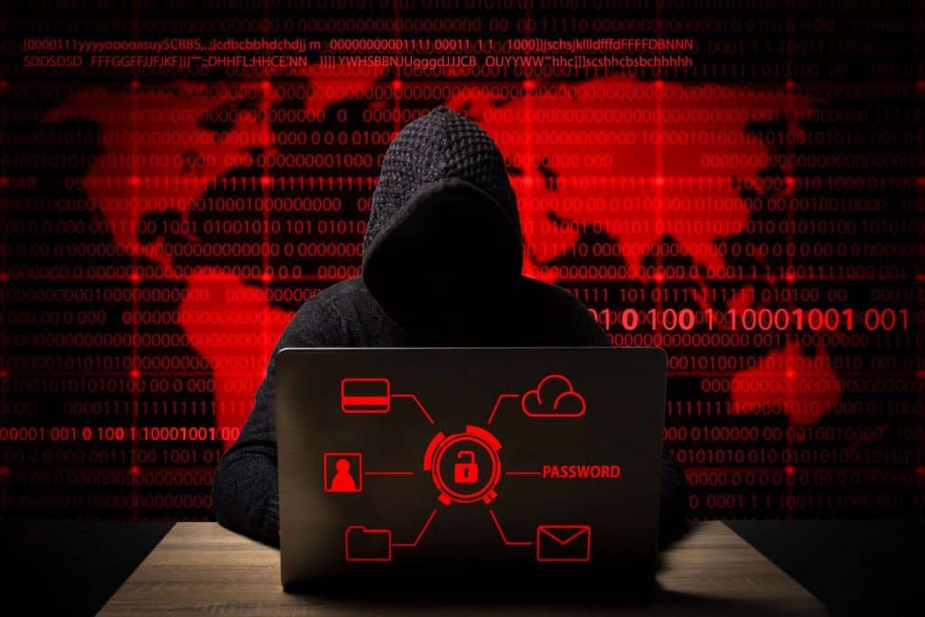 hacker tapado con capucha utilizando un portátil e intentando hackear la Ciberseguridad pyme